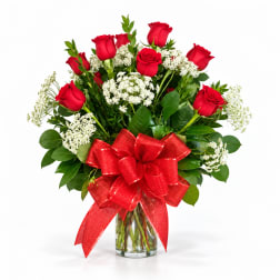 Red roses in a clear glass vase with a large red bow