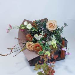 Bouquet of peach roses and mixed flowers in a rustic box