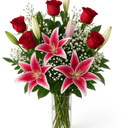 Red roses and pink lilies in a clear glass vase