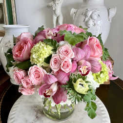 Pink roses and orchids arranged in a clear glass vase