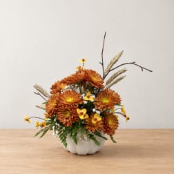 Orange chrysanthemum arrangement in a white pumpkin-shaped vase