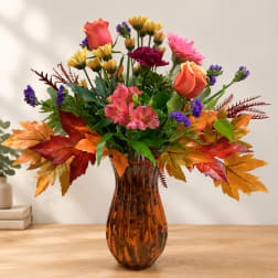Mixed bouquet in an amber glass vase with orange, pink, and purple flowers