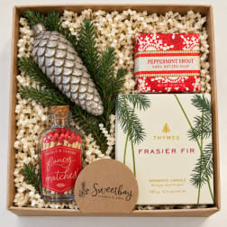 Holiday gift box with a candle, soap, matches, and a silver pinecone ornament