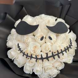 White rose bouquet wrapped in black paper with a skull face design