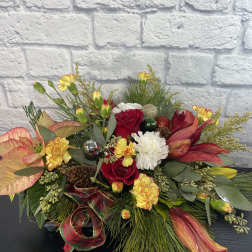 Festive floral arrangement with red roses, white carnations, and lilies in a low design