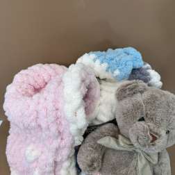 Plush teddy bear with pastel blankets in a box