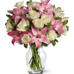 Clear glass vase with white roses and pink lilies arranged in a rounded bouquet