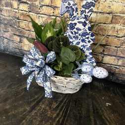 Green houseplants in a white basket with blue patterned bunny and egg decorations
