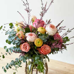 Mixed pink and peach flowers in a glass vase with eucalyptus