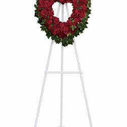 Heart-shaped wreath of red roses on a white easel
