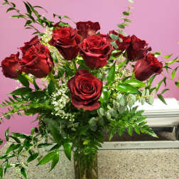 Red roses arranged in a clear glass vase with greenery
