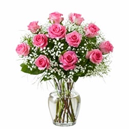 Pink roses arranged in a clear glass vase with white filler flowers