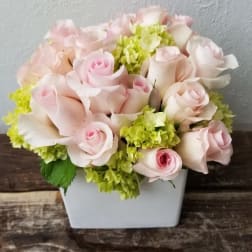 Pink roses and green hydrangeas in a white square vase