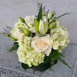 Cream roses and white lilies arranged in a low vase