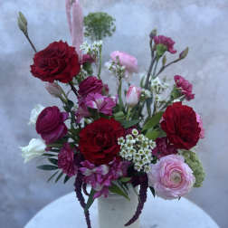 Mixed bouquet of red, pink, and white flowers in a white vase