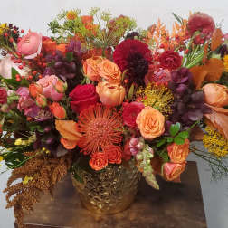 Large autumn bouquet with orange, red, and pink flowers in a gold vase