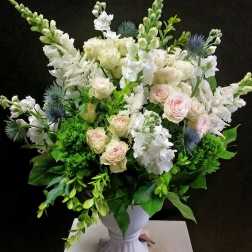 White and blush bouquet in a white pedestal vase