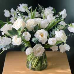 White roses and ranunculus in a clear glass vase