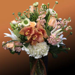 Mixed bouquet with orchids, roses, lilies, and hydrangea in a glass vase
