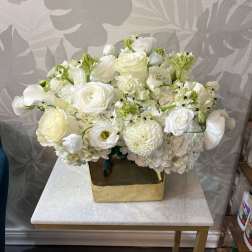White floral arrangement in a gold square vase