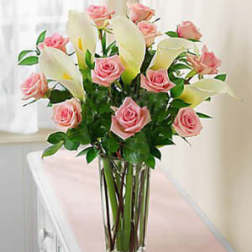 Pink roses and white calla lilies in a tall glass vase
