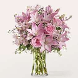 Pink lilies and roses arranged in a clear glass vase