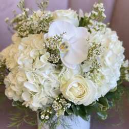 White floral arrangement in a round box with roses and hydrangeas