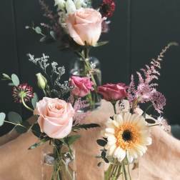 Small mixed bouquets in glass vases with roses and a gerbera daisy