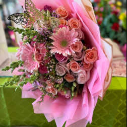 Pink bouquet of roses and gerbera daisies wrapped in pink paper