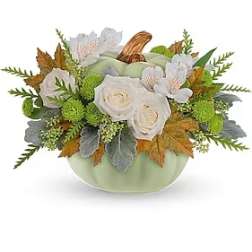 White roses in a pale green pumpkin-shaped container with autumn leaves