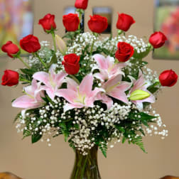 Red roses and pink lilies arranged in a clear glass vase