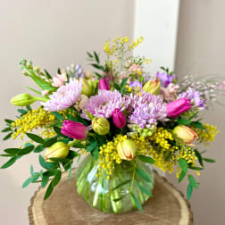 Mixed bouquet of pink and lavender flowers in a glass vase