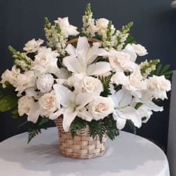 White lilies and roses arranged in a wicker basket