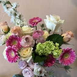 Handheld bouquet of pink, cream, and green flowers