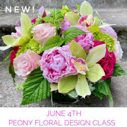 Low arrangement of pink peonies, roses, orchids, and hydrangea in a clear glass vase