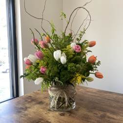 Tulip arrangement in a glass vase with curly branches