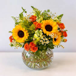 Sunflower and orange rose arrangement in a round glass vase