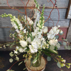 White floral arrangement in a glass vase with curly branches