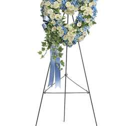 Heart-shaped floral wreath on a standing easel with blue and white flowers
