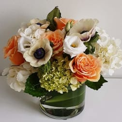 Bouquet of peach, white, and cream flowers in a glass vase