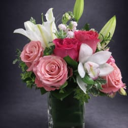 Pink roses and white lilies arranged in a clear glass vase