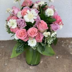 Pink and lavender roses arranged with white daisies in a green vase