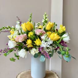 Yellow and pink roses in a light blue vase with white blooms