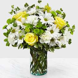 Yellow roses and white daisies in a clear glass vase