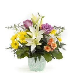 Mixed bouquet with lilies, roses, and yellow daisies in a patterned vase