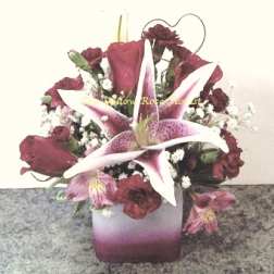 Pink lilies and dark red roses arranged in a square vase