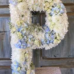 Large floral letter P made of white and pale blue flowers