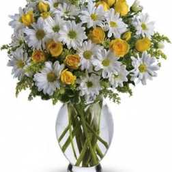 White daisies and yellow roses in a clear glass vase