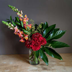 Red chrysanthemums and pink snapdragons in a clear glass vase