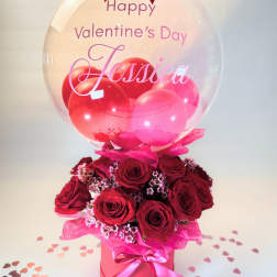 Red roses in a pink box with a clear balloon and Valentine’s Day message